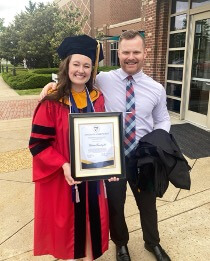 Victoria Courtright in graduation robes holding honor