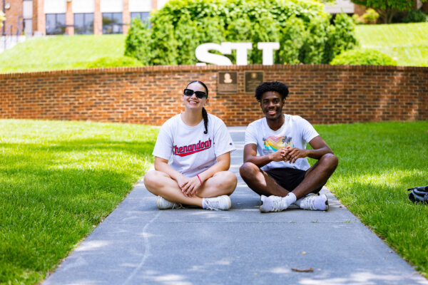 Two students in front of 皇冠博彩 statue